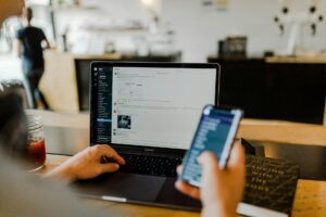 Student using social channels on phone and laptop